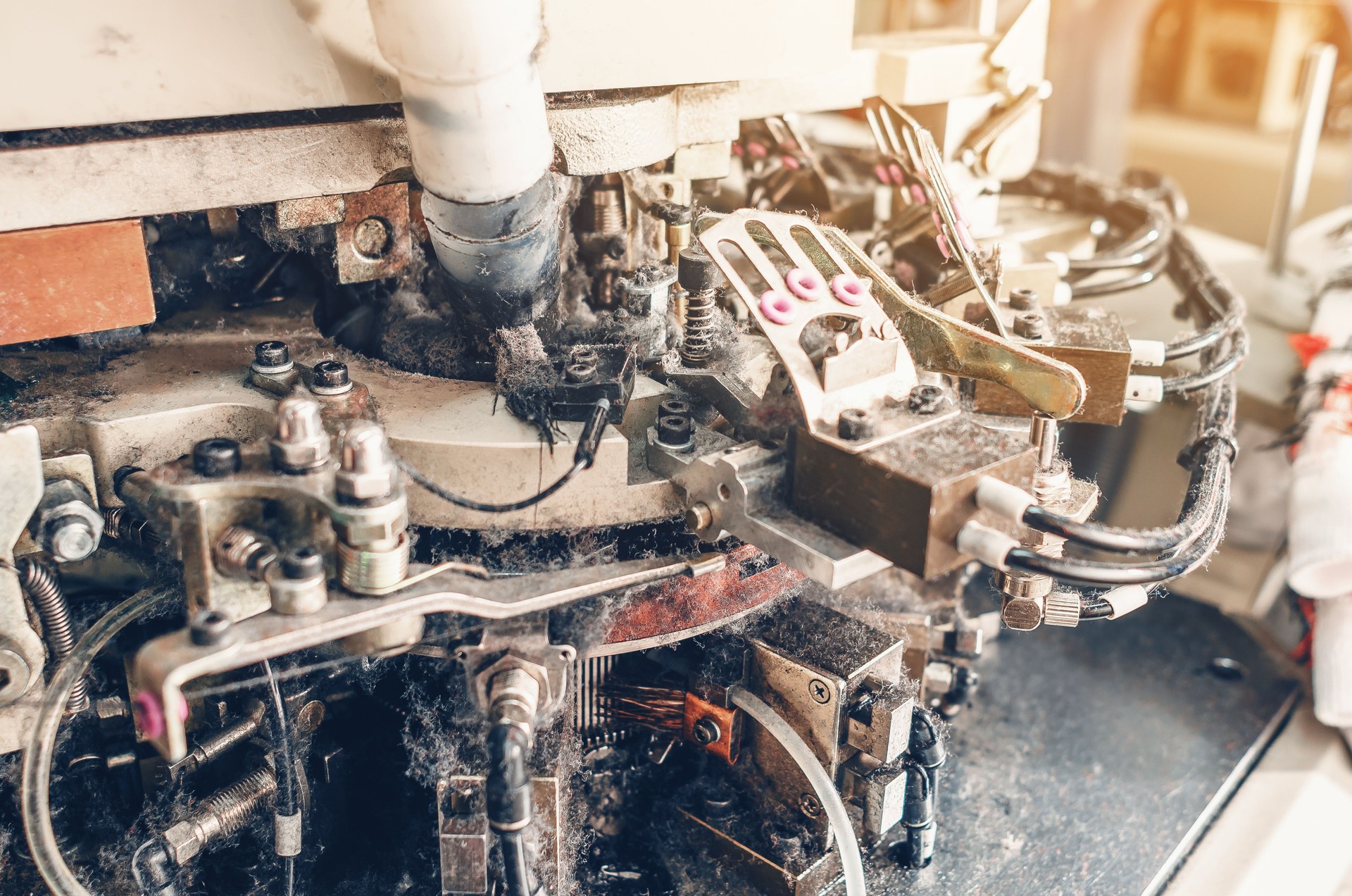 Part of sock knitting machine in operation. Dust from threads. Equipment in textile production.